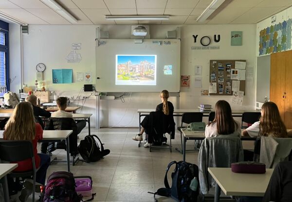 Schüler:innen hören der online zugeschalteten Archäologin zu und sehen sich den geteilten Bildschirm an.